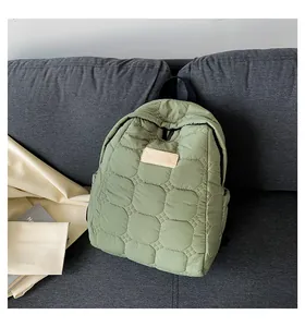 Detail of sage green quilted backpack fabric texture and square minimalist brand patch