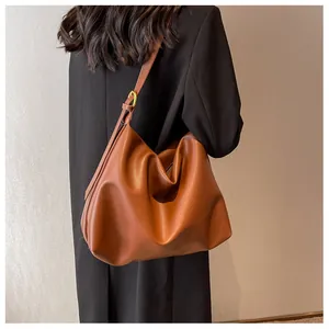 Side view of a brown leather Hobo bag with adjustable strap on a female model