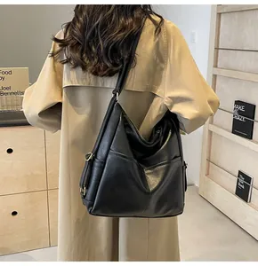 Side detail of a black faux leather tote bag with adjustable metal buckle on shoulder strap