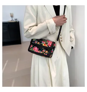 Detailed view of crossbody bag with floral pattern on a beige blazer model outfit