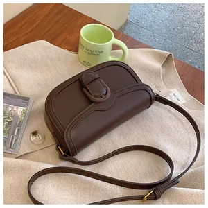 Détail du sac à bandoulière en cuir chocolat avec boucle sur fond en maille douce