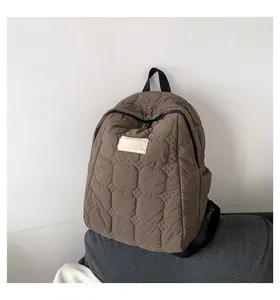 Detail of dark brown quilted backpack with circular padding and white logo patch