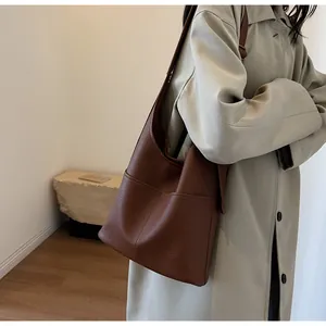 Detail of dark brown lychee leather bucket bag showing texture and side pocket design