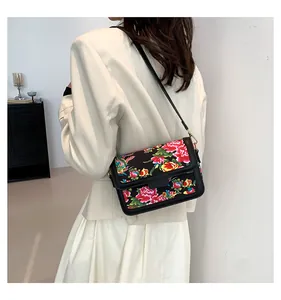 Detail of crossbody bag featuring traditional Chinese floral peony pattern and leather strap