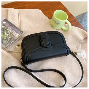 Gros plan d'un sac besace vintage en cuir noir posé sur une table en bois massif