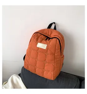 Detailed view of the bright orange quilted texture and white label on the backpack