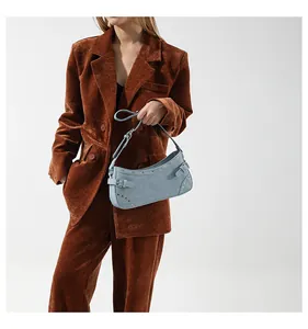 Détail du sac sous l'aisselle en denim bleu clair avec rivets argentés et boucle