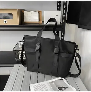 Détail du sac fourre-tout noir en oxford avec boucles techniques sur surface métallique