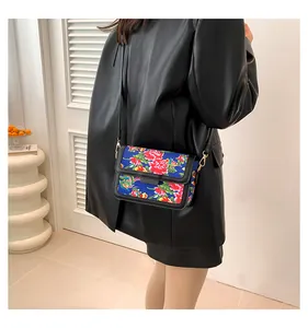 Detailed view of crossbody bag with traditional phoenix pattern and leather accents
