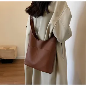 Detail of dark brown pebble leather hobo bag showing stitching on front pocket