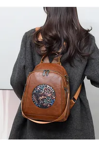 Detail of vintage brown leather backpack with ethnic elephant embroidery and zipper