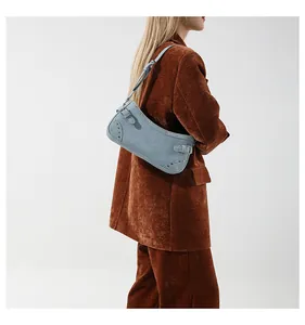 Vue détaillée du sac baguette en jean bleu clair avec rivets porté par un mannequin