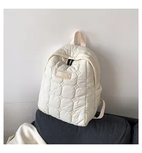 Detailed view of cream-white quilted backpack with cloud pattern stitching on sofa