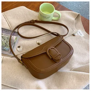 Détail d'un sac besace en cuir marron avec rabat et boucle sur un manteau beige élégant