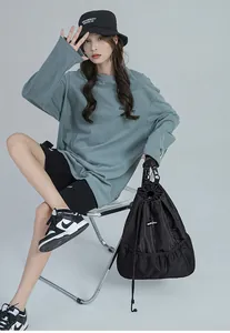 Détail d'un sac à dos en nylon noir avec cordon de serrage et poches latérales en filet