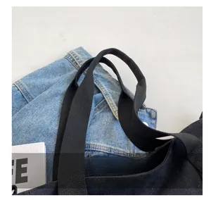 Close-up of reinforced woven handles on a large black canvas tote bag for daily use