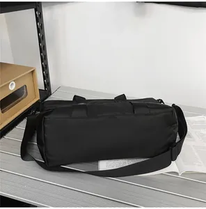 Détail du sac de voyage noir en tissu oxford avec poignées renforcées et bandoulière