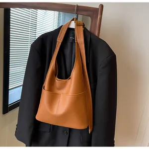 Macro detail of brown lychee grain leather bucket bag with wide strap and bronze buckle