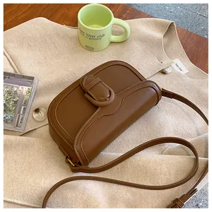 Détail d'un sac bandoulière vintage en cuir marron avec boucle ovale et fine bandoulière