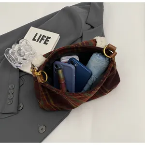 Top view of spacious plaid shoulder bag interior holding phone, umbrella, and cosmetics