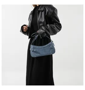 Détail du sac hobo en denim bleu avec rivets argentés et boucle de style rétro