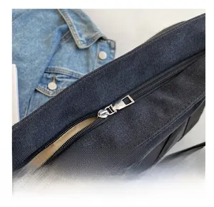 Close-up of smooth silver metal zipper on a black canvas tote bag with brown lining