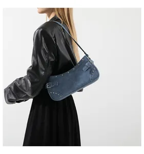 Sac à bandoulière en jean rétro avec clous argentés et boucles porté par un mannequin