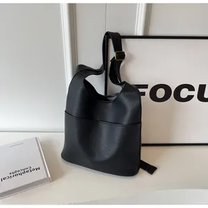 Detail of black pebbled leather bucket bag featuring a gold buckle and front pocket