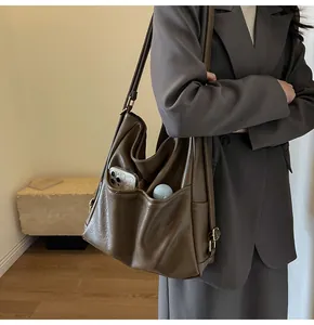 Detail of a large brown faux leather tote bag with functional front storage pockets