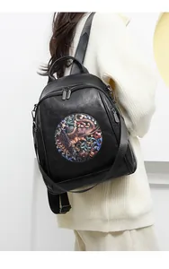 Detail of black leather backpack featuring colorful elephant patch and metal zipper
