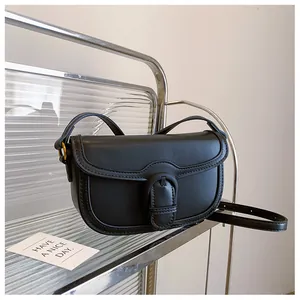 Détail d'un sac besace vintage en cuir noir avec grande boucle et bandoulière réglable