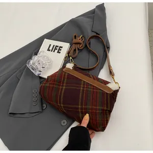 Detail of retro plaid shoulder bag with wool fabric and brown leather strap on blazer