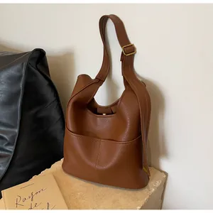 Close-up of brown lychee grain leather bucket bag with adjustable strap and gold hardware