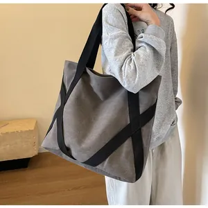 Detailansicht einer grauen Canvas-Tragetasche mit schwarzen Trägern am Model