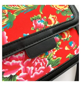 Detail of red floral crossbody bag featuring traditional phoenix embroidery and leather trim