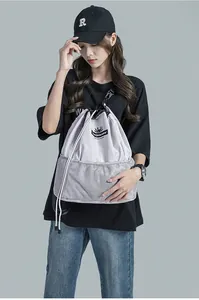 Détail du sac à dos gris clair à cordon avec poche en filet et logo de monstre dessin