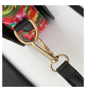Close-up of golden metal lobster clasp and black lychee leather strap with floral print