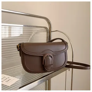 Détail du sac selle vintage marron foncé avec rabat arrondi et boucle circulaire