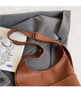 Detailed close-up of brown pebbled leather bucket bag with adjustable shoulder strap