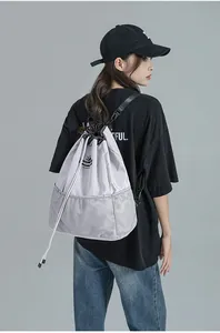 Détail du sac à dos gris clair à cordon avec fond en maille porté par un mannequin