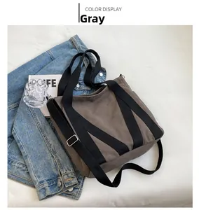 Detail view of the grey canvas tote bag showing durable texture and black shoulder straps