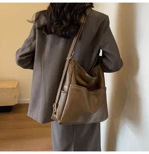 Detail of vintage brown large capacity tote bag with adjustable shoulder strap on model