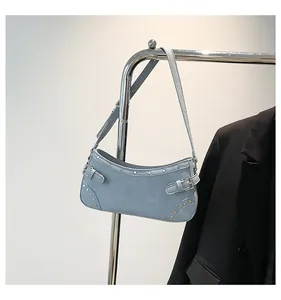 Détail du sac sous l'aisselle en denim bleu clair avec rivets argentés