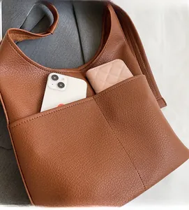 Detail shot of a brown pebbled leather bag featuring a large functional front pocket