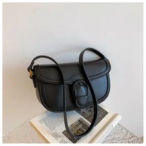 Détail du sac en cuir noir mat avec ferrures dorées et bandoulière large sur magazine