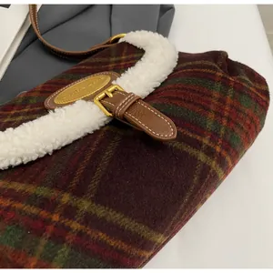 Detail of wool plaid handbag with faux shearling trim and brown leather buckle strap