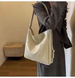 Detail of creamy white large capacity tote bag with soft pleated leather texture and gold buckle