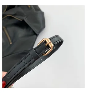Close-up of black leather shoulder strap with gold buckle and precise stitching