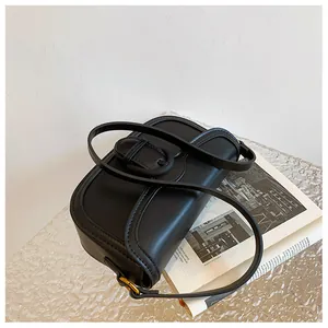 Gros plan détaillé d'un sac à bandoulière en cuir noir mat sur une surface en verre
