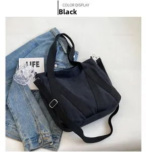 Detail of a black canvas tote bag with adjustable strap and textured fabric finish